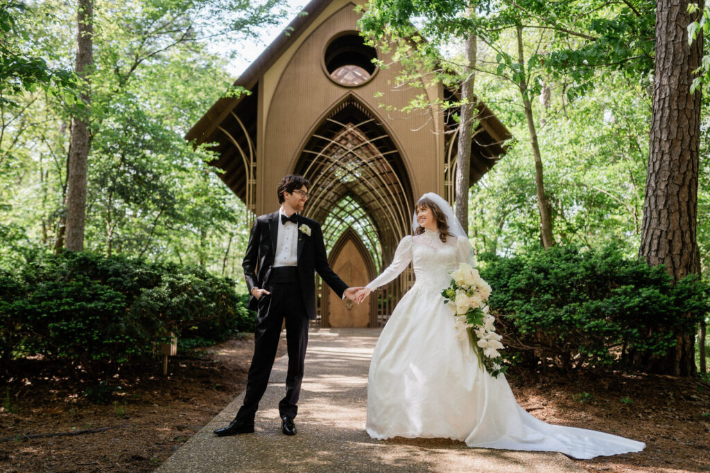 Newlyweds hold hands in front of Mildred B Cooper Chapel