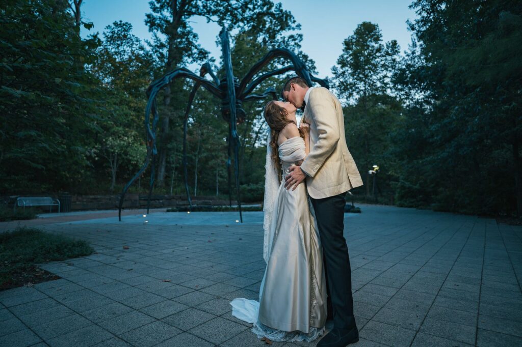 Newlyweds kiss by sculpture at Crystal Bridges